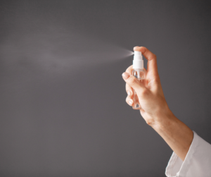 Hand using hand sanitizer to disinfect a surface.