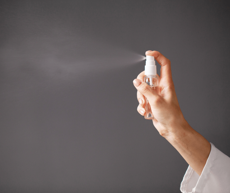 Hand using hand sanitizer to disinfect a surface.